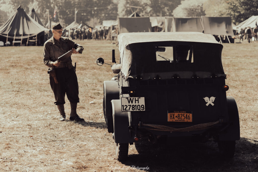 A group of World War II reenactors in period-accurate uniforms—American, German, and French Resistance—on a sandy shore during the D-Day Conneaut 2025 reenactment at Conneaut Township Park, Ohio.