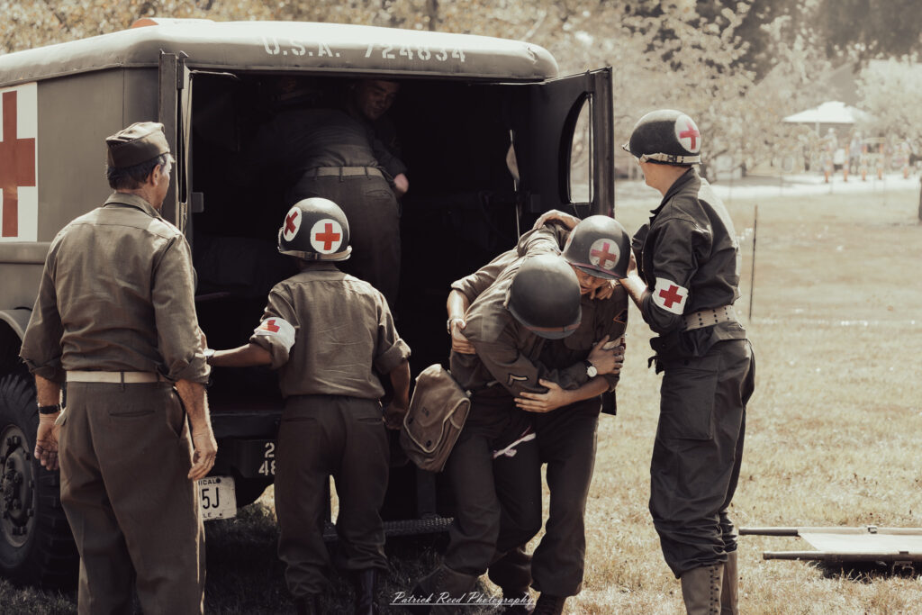 A group of World War II reenactors in period-accurate uniforms—American, German, and French Resistance—on a sandy shore during the D-Day Conneaut 2025 reenactment at Conneaut Township Park, Ohio.
