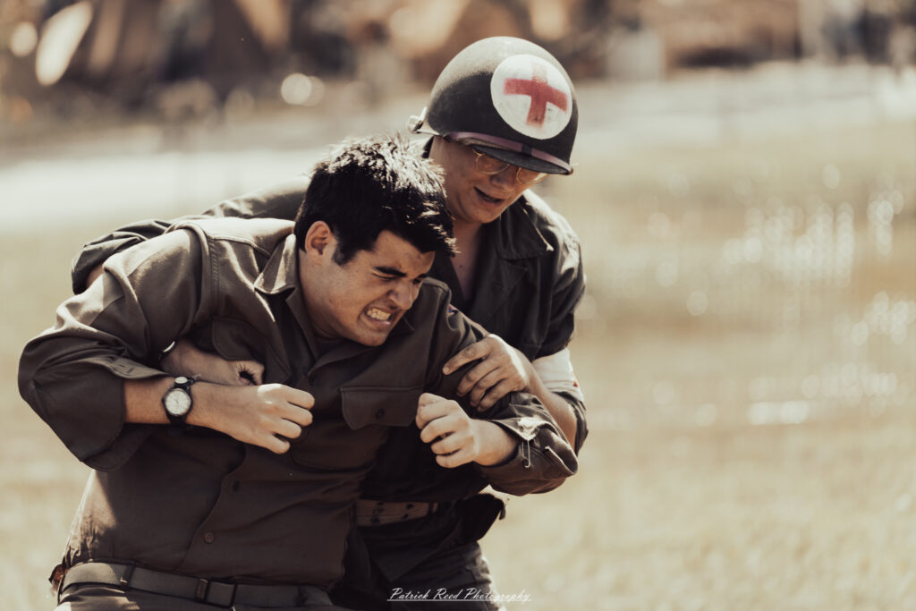 A group of World War II reenactors in period-accurate uniforms—American, German, and French Resistance—on a sandy shore during the D-Day Conneaut 2025 reenactment at Conneaut Township Park, Ohio.
