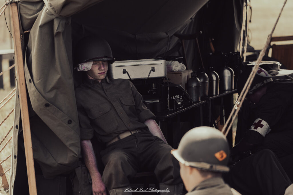 A group of World War II reenactors in period-accurate uniforms—American, German, and French Resistance—on a sandy shore during the D-Day Conneaut 2025 reenactment at Conneaut Township Park, Ohio.