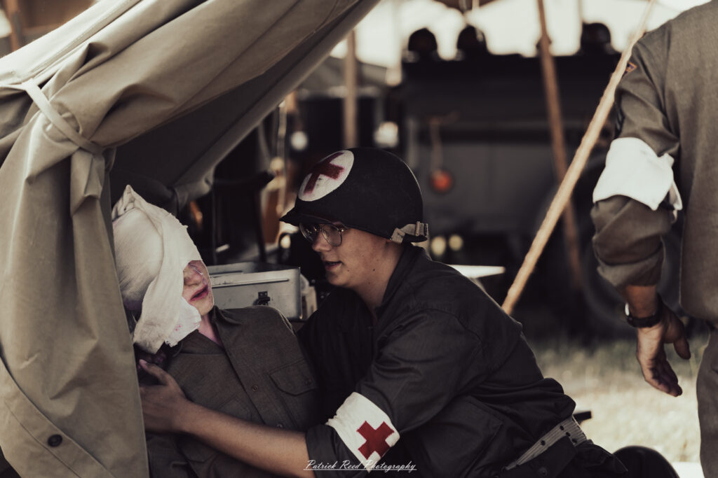 A group of World War II reenactors in period-accurate uniforms—American, German, and French Resistance—on a sandy shore during the D-Day Conneaut 2025 reenactment at Conneaut Township Park, Ohio.