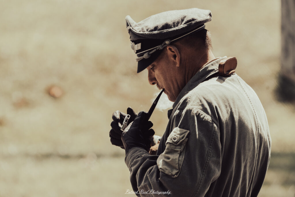 A group of World War II reenactors in period-accurate uniforms—American, German, and French Resistance—on a sandy shore during the D-Day Conneaut 2025 reenactment at Conneaut Township Park, Ohio.