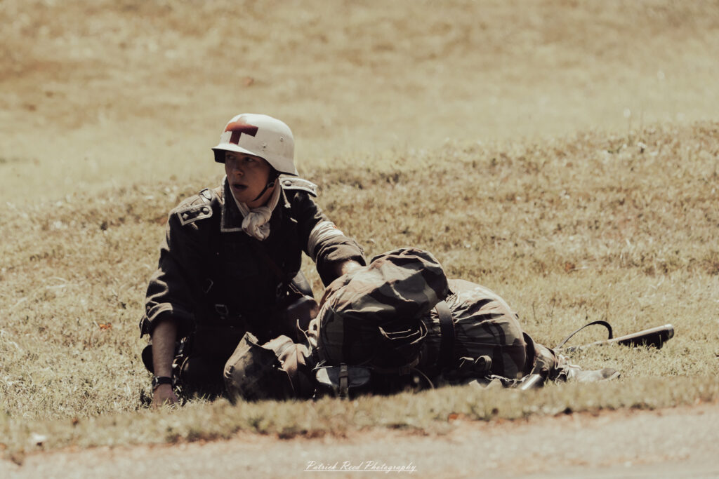 A group of World War II reenactors in period-accurate uniforms—American, German, and French Resistance—on a sandy shore during the D-Day Conneaut 2025 reenactment at Conneaut Township Park, Ohio.