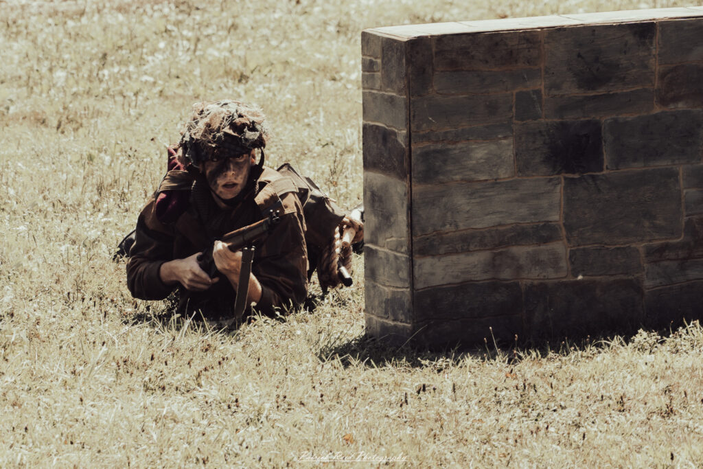 A group of World War II reenactors in period-accurate uniforms—American, German, and French Resistance—on a sandy shore during the D-Day Conneaut 2025 reenactment at Conneaut Township Park, Ohio.