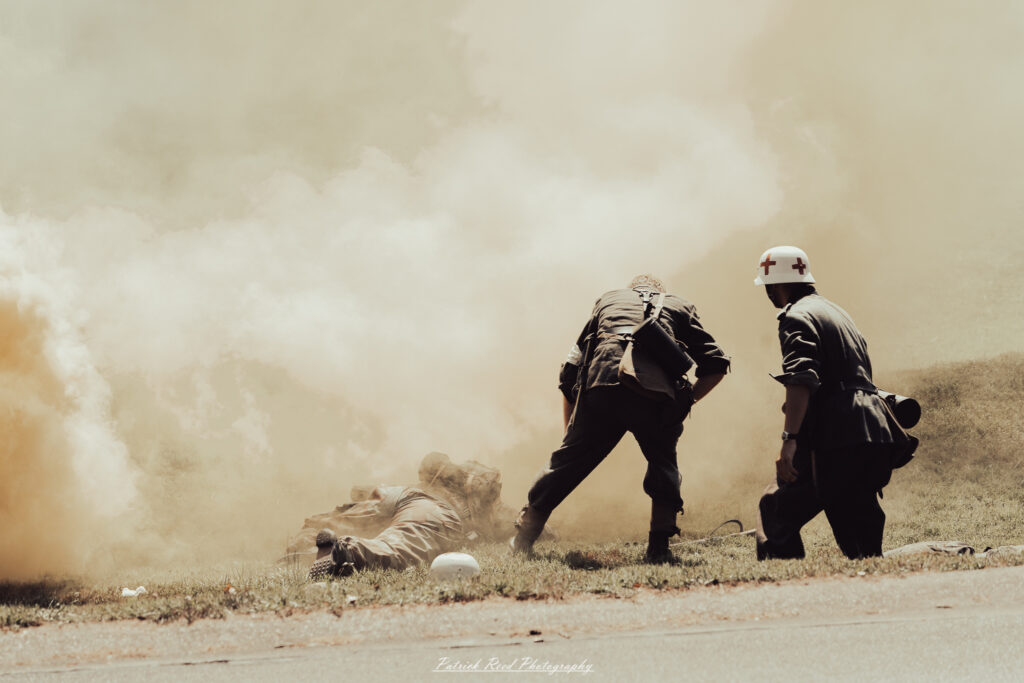 A group of World War II reenactors in period-accurate uniforms—American, German, and French Resistance—on a sandy shore during the D-Day Conneaut 2025 reenactment at Conneaut Township Park, Ohio.