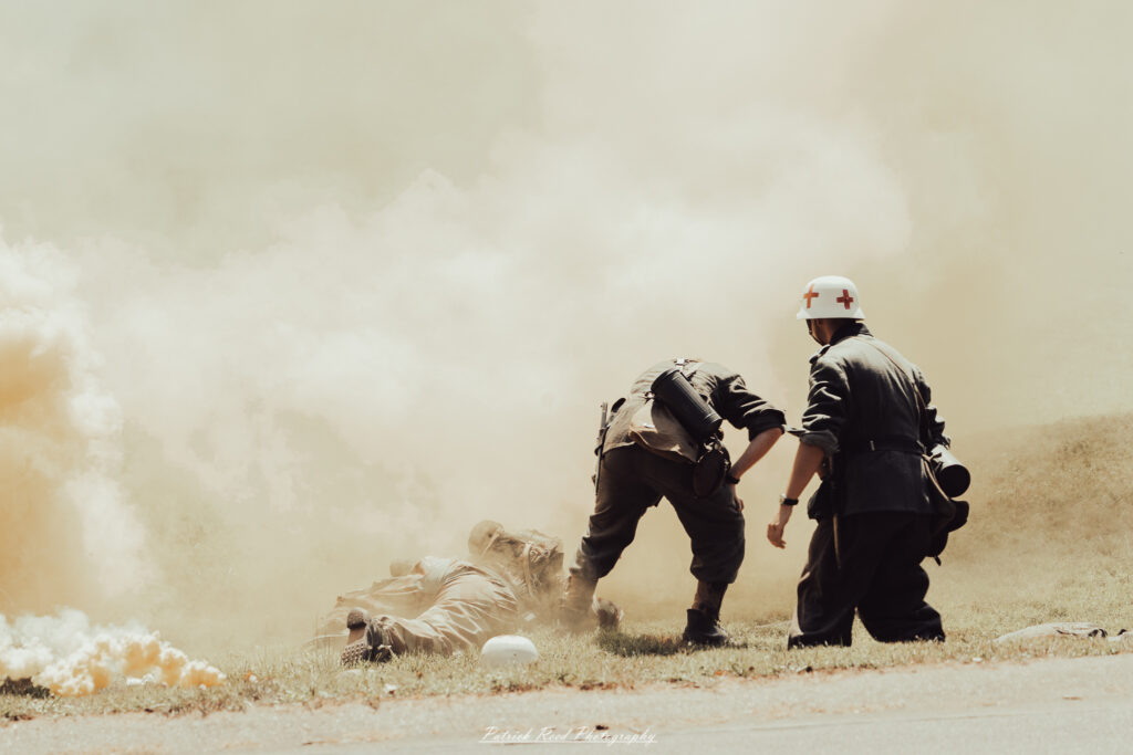 A group of World War II reenactors in period-accurate uniforms—American, German, and French Resistance—on a sandy shore during the D-Day Conneaut 2025 reenactment at Conneaut Township Park, Ohio.