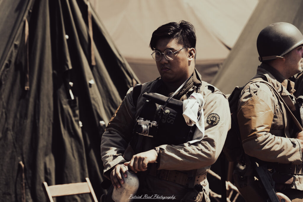 A group of World War II reenactors in period-accurate uniforms—American, German, and French Resistance—on a sandy shore during the D-Day Conneaut 2025 reenactment at Conneaut Township Park, Ohio.