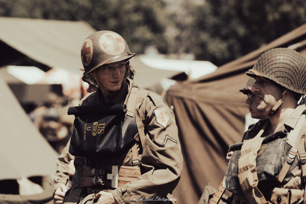 A group of World War II reenactors in period-accurate uniforms—American, German, and French Resistance—on a sandy shore during the D-Day Conneaut 2025 reenactment at Conneaut Township Park, Ohio.