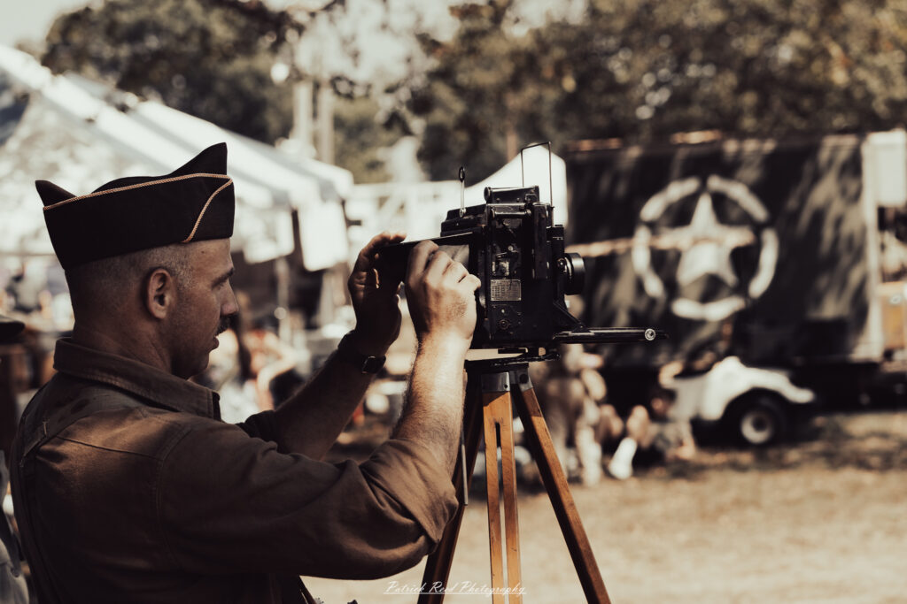 A group of World War II reenactors in period-accurate uniforms—American, German, and French Resistance—on a sandy shore during the D-Day Conneaut 2025 reenactment at Conneaut Township Park, Ohio.