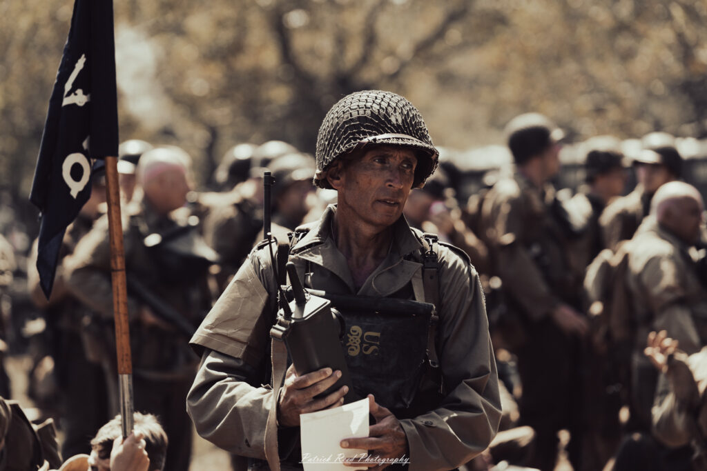 A group of World War II reenactors in period-accurate uniforms—American, German, and French Resistance—on a sandy shore during the D-Day Conneaut 2025 reenactment at Conneaut Township Park, Ohio.