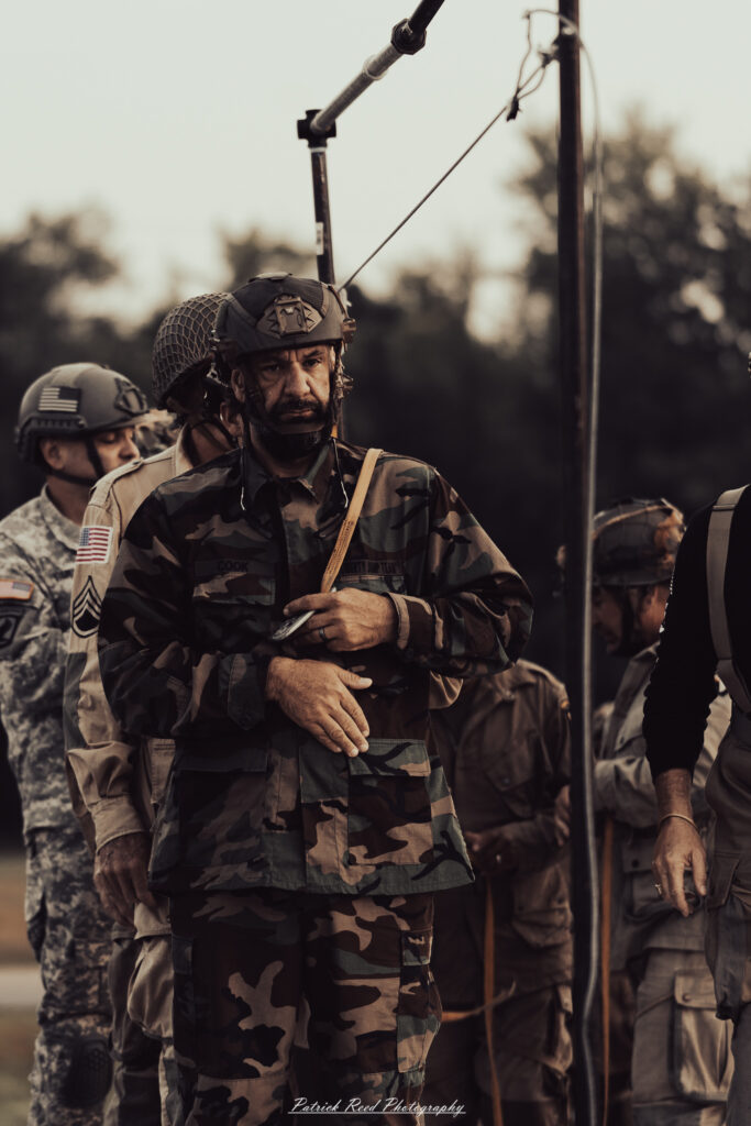A group of World War II reenactors in period-accurate uniforms—American, German, and French Resistance—on a sandy shore during the D-Day Conneaut 2025 reenactment at Conneaut Township Park, Ohio.