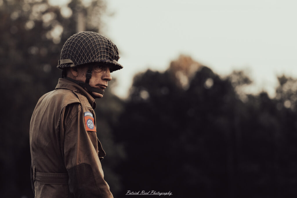 A group of World War II reenactors in period-accurate uniforms—American, German, and French Resistance—on a sandy shore during the D-Day Conneaut 2025 reenactment at Conneaut Township Park, Ohio.