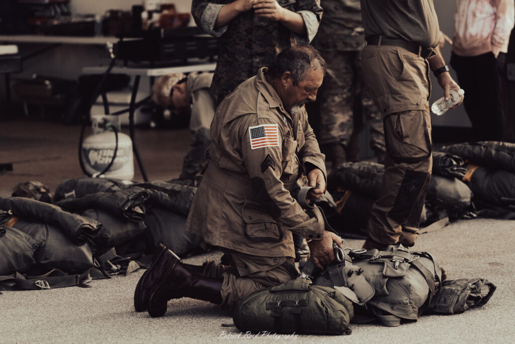A group of World War II reenactors in period-accurate uniforms—American, German, and French Resistance—on a sandy shore during the D-Day Conneaut 2025 reenactment at Conneaut Township Park, Ohio.