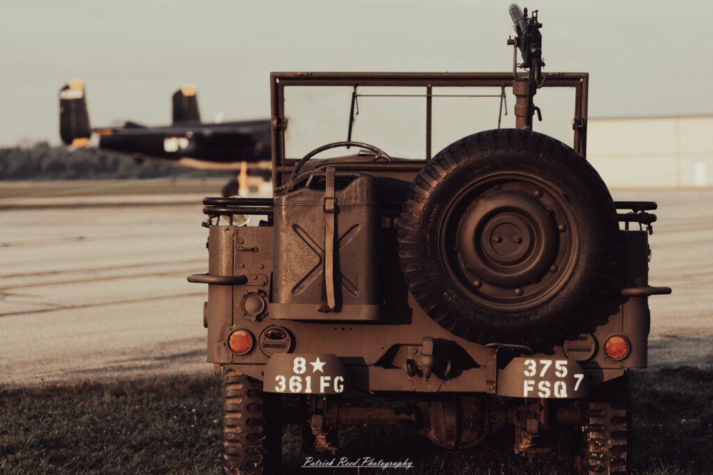 A group of World War II reenactors in period-accurate uniforms—American, German, and French Resistance—on a sandy shore during the D-Day Conneaut 2025 reenactment at Conneaut Township Park, Ohio.