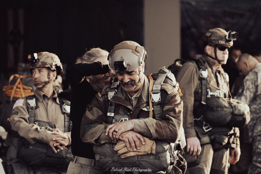 A group of World War II reenactors in period-accurate uniforms—American, German, and French Resistance—on a sandy shore during the D-Day Conneaut 2025 reenactment at Conneaut Township Park, Ohio.