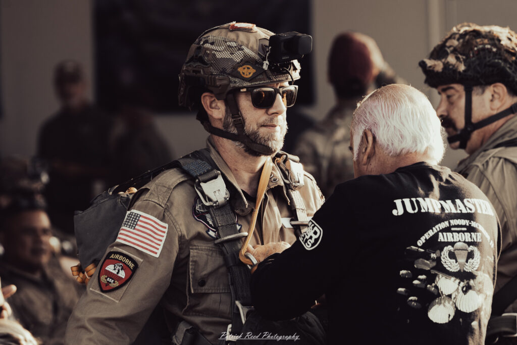 A group of World War II reenactors in period-accurate uniforms—American, German, and French Resistance—on a sandy shore during the D-Day Conneaut 2025 reenactment at Conneaut Township Park, Ohio.