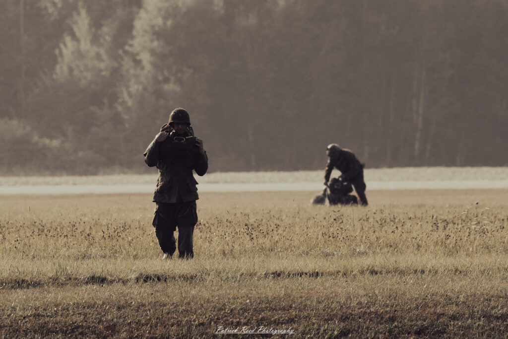 A group of World War II reenactors in period-accurate uniforms—American, German, and French Resistance—on a sandy shore during the D-Day Conneaut 2025 reenactment at Conneaut Township Park, Ohio.