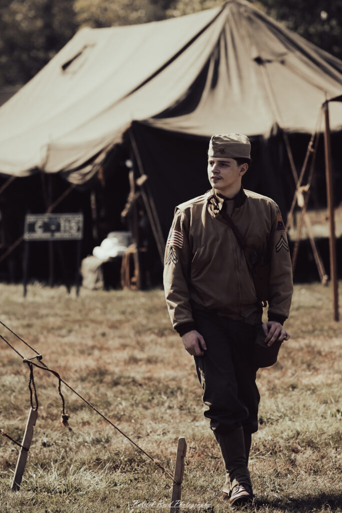 A group of World War II reenactors in period-accurate uniforms—American, German, and French Resistance—on a sandy shore during the D-Day Conneaut 2025 reenactment at Conneaut Township Park, Ohio.