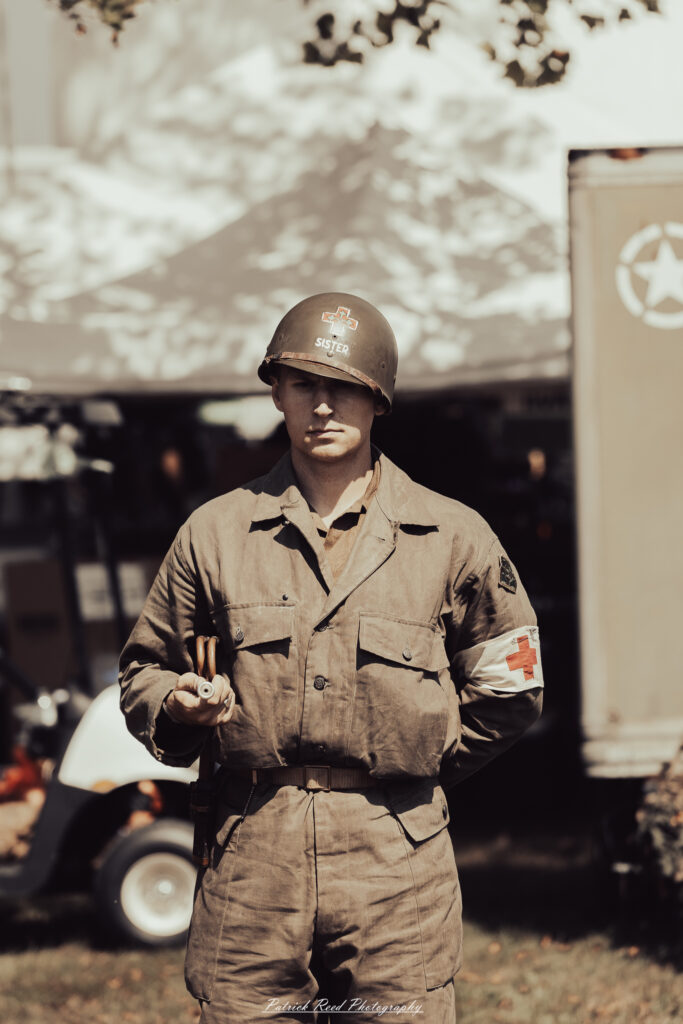 A group of World War II reenactors in period-accurate uniforms—American, German, and French Resistance—on a sandy shore during the D-Day Conneaut 2025 reenactment at Conneaut Township Park, Ohio.