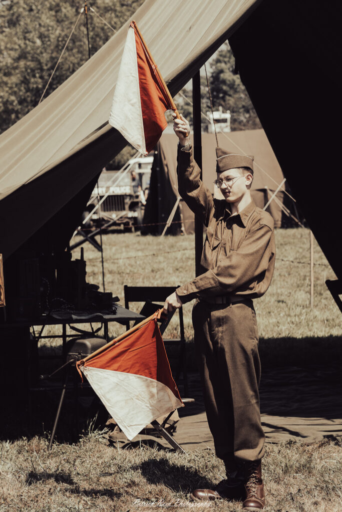 A group of World War II reenactors in period-accurate uniforms—American, German, and French Resistance—on a sandy shore during the D-Day Conneaut 2025 reenactment at Conneaut Township Park, Ohio.