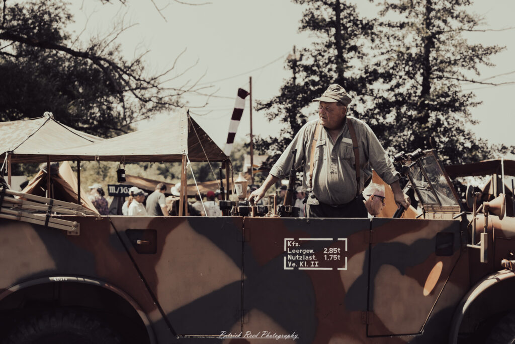 A group of World War II reenactors in period-accurate uniforms—American, German, and French Resistance—on a sandy shore during the D-Day Conneaut 2025 reenactment at Conneaut Township Park, Ohio.