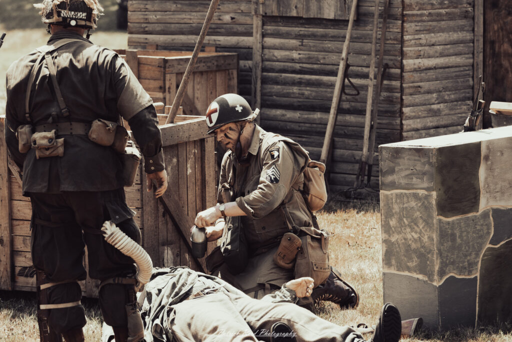 A group of World War II reenactors in period-accurate uniforms—American, German, and French Resistance—on a sandy shore during the D-Day Conneaut 2025 reenactment at Conneaut Township Park, Ohio.