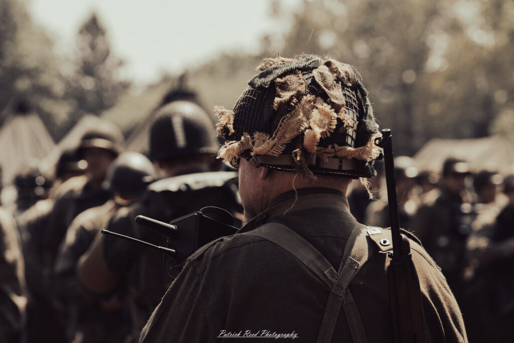 A group of World War II reenactors in period-accurate uniforms—American, German, and French Resistance—on a sandy shore during the D-Day Conneaut 2025 reenactment at Conneaut Township Park, Ohio.