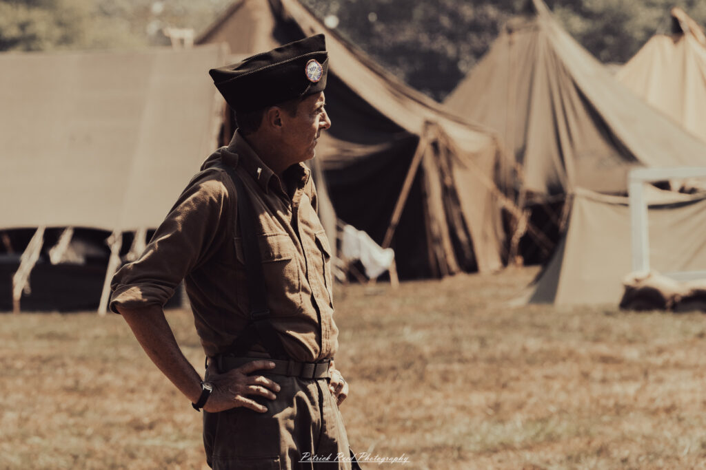 A group of World War II reenactors in period-accurate uniforms—American, German, and French Resistance—on a sandy shore during the D-Day Conneaut 2025 reenactment at Conneaut Township Park, Ohio.