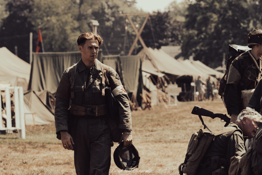 A group of World War II reenactors in period-accurate uniforms—American, German, and French Resistance—on a sandy shore during the D-Day Conneaut 2025 reenactment at Conneaut Township Park, Ohio.