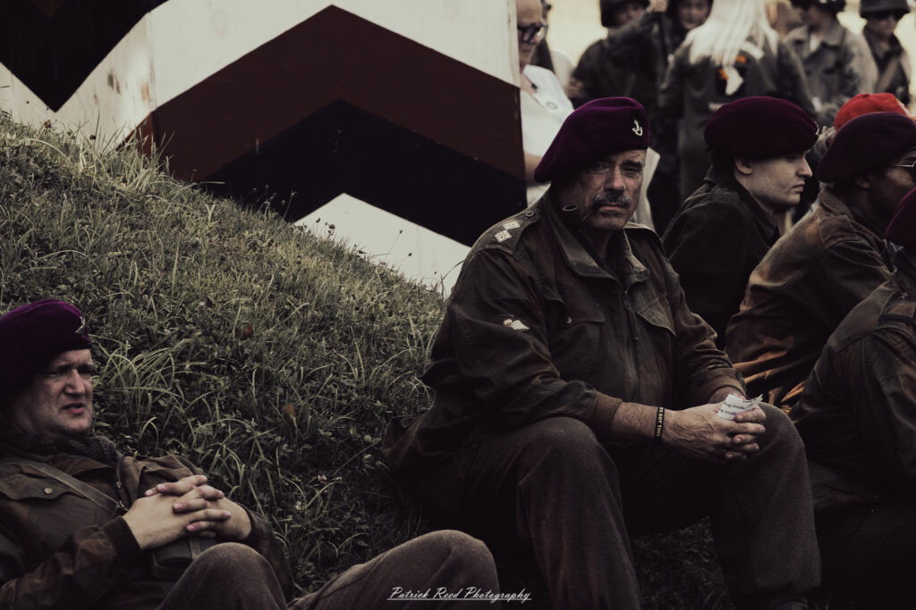 A group of World War II reenactors in period-accurate uniforms—American, German, and French Resistance—on a sandy shore during the D-Day Conneaut 2025 reenactment at Conneaut Township Park, Ohio.