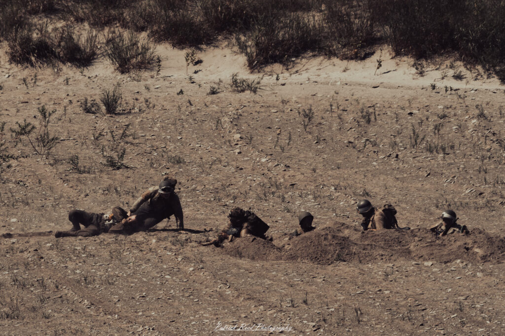 A group of World War II reenactors in period-accurate uniforms—American, German, and French Resistance—on a sandy shore during the D-Day Conneaut 2025 reenactment at Conneaut Township Park, Ohio.