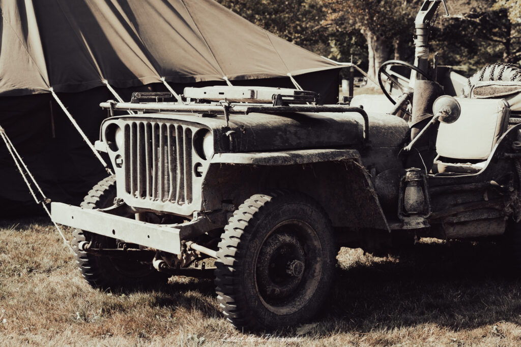 A group of World War II reenactors in period-accurate uniforms—American, German, and French Resistance—on a sandy shore during the D-Day Conneaut 2025 reenactment at Conneaut Township Park, Ohio.