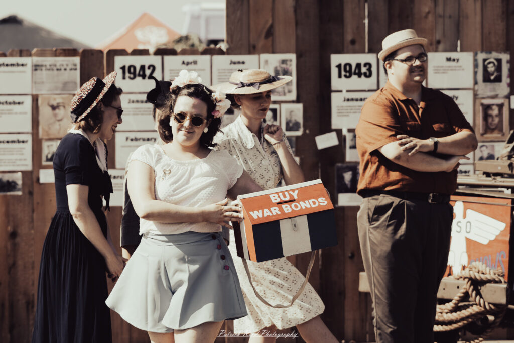 A group of World War II reenactors in period-accurate uniforms—American, German, and French Resistance—on a sandy shore during the D-Day Conneaut 2025 reenactment at Conneaut Township Park, Ohio.