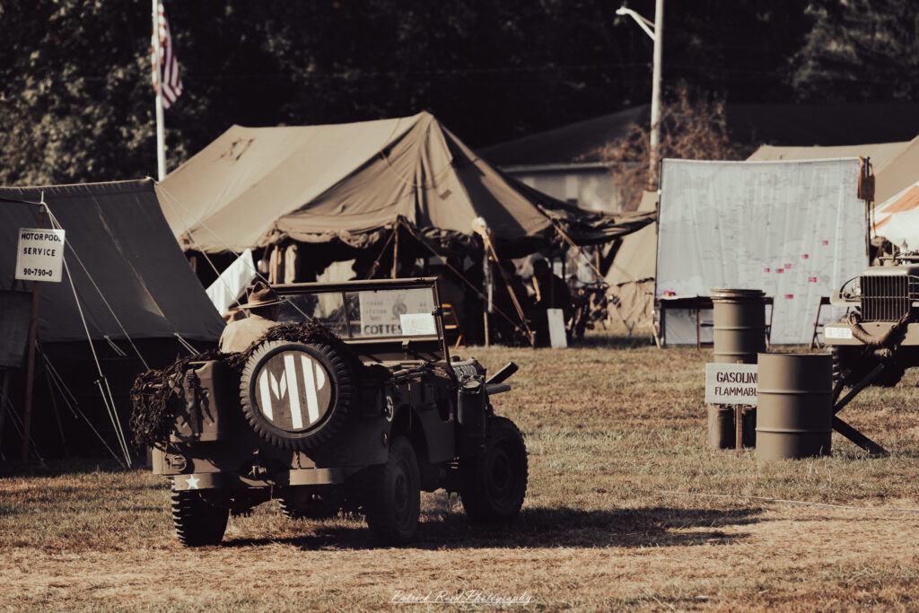 A group of World War II reenactors in period-accurate uniforms—American, German, and French Resistance—on a sandy shore during the D-Day Conneaut 2025 reenactment at Conneaut Township Park, Ohio.