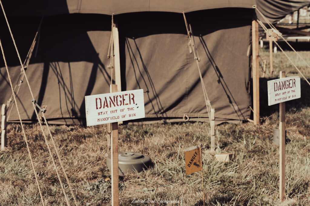 A group of World War II reenactors in period-accurate uniforms—American, German, and French Resistance—on a sandy shore during the D-Day Conneaut 2025 reenactment at Conneaut Township Park, Ohio.