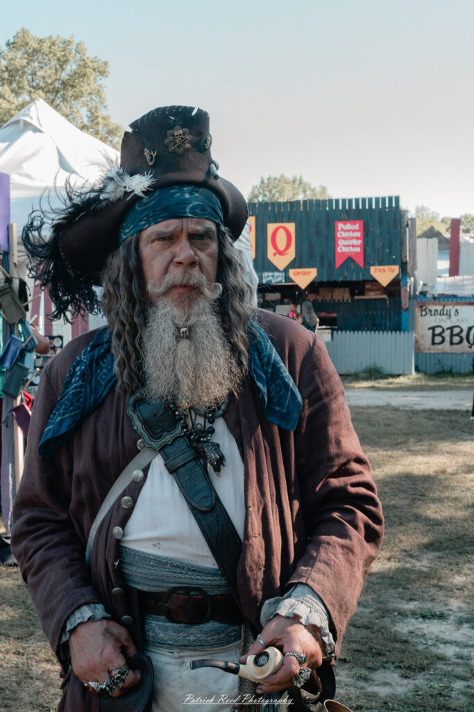A costumed performer at the Michigan Renaissance Festival 2025, wearing traditional Renaissance attire during a live event in Holly, Michigan.