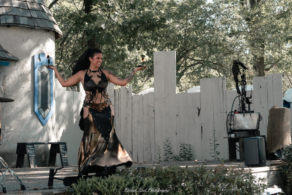 A costumed performer at the Michigan Renaissance Festival 2025, wearing traditional Renaissance attire during a live event in Holly, Michigan.