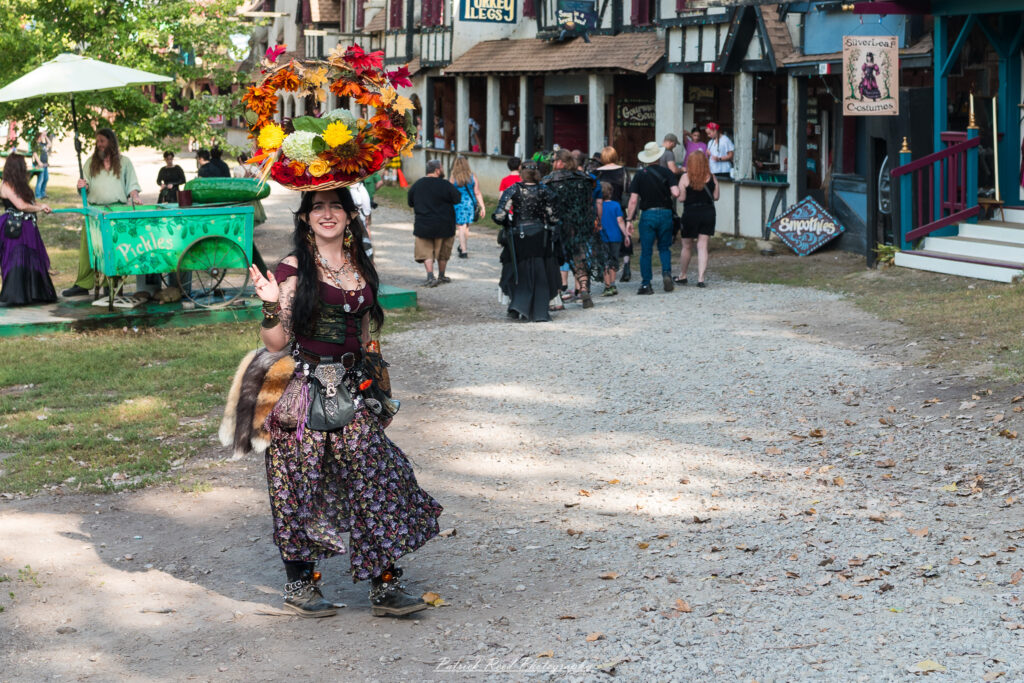 A costumed performer at the Michigan Renaissance Festival 2025, wearing traditional Renaissance attire during a live event in Holly, Michigan.