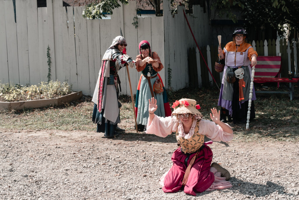 A costumed performer at the Michigan Renaissance Festival 2025, wearing traditional Renaissance attire during a live event in Holly, Michigan.