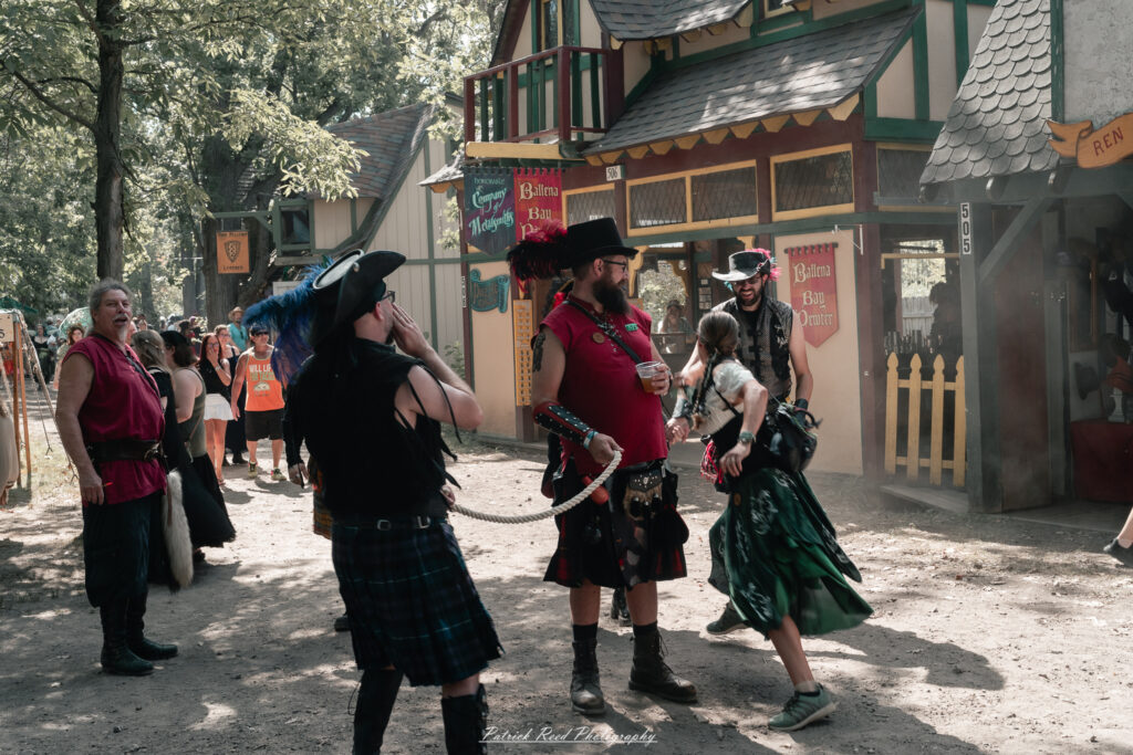 A costumed performer at the Michigan Renaissance Festival 2025, wearing traditional Renaissance attire during a live event in Holly, Michigan.