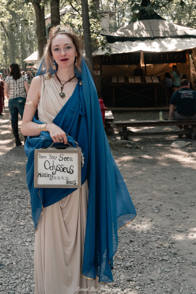 A costumed performer at the Michigan Renaissance Festival 2025, wearing traditional Renaissance attire during a live event in Holly, Michigan.