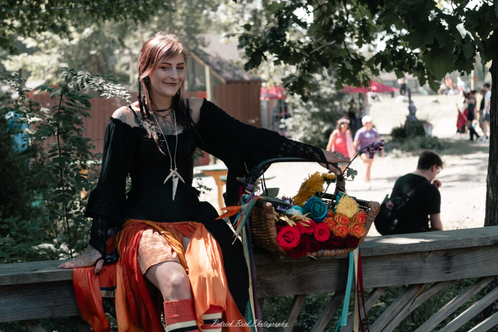 A costumed performer at the Michigan Renaissance Festival 2025, wearing traditional Renaissance attire during a live event in Holly, Michigan.