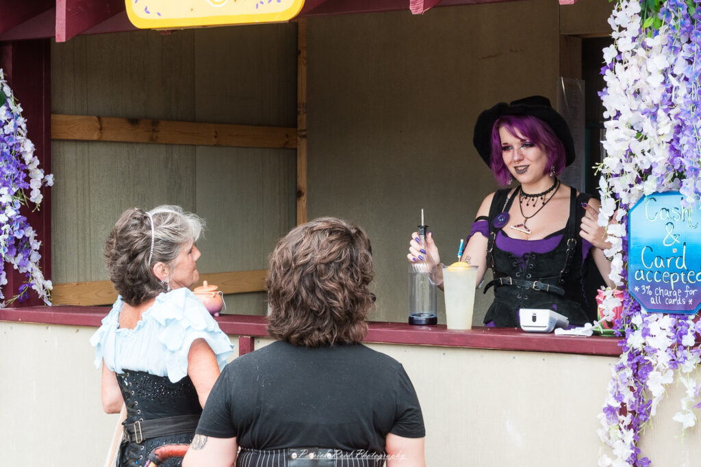 A costumed performer at the Michigan Renaissance Festival 2025, wearing traditional Renaissance attire during a live event in Holly, Michigan.