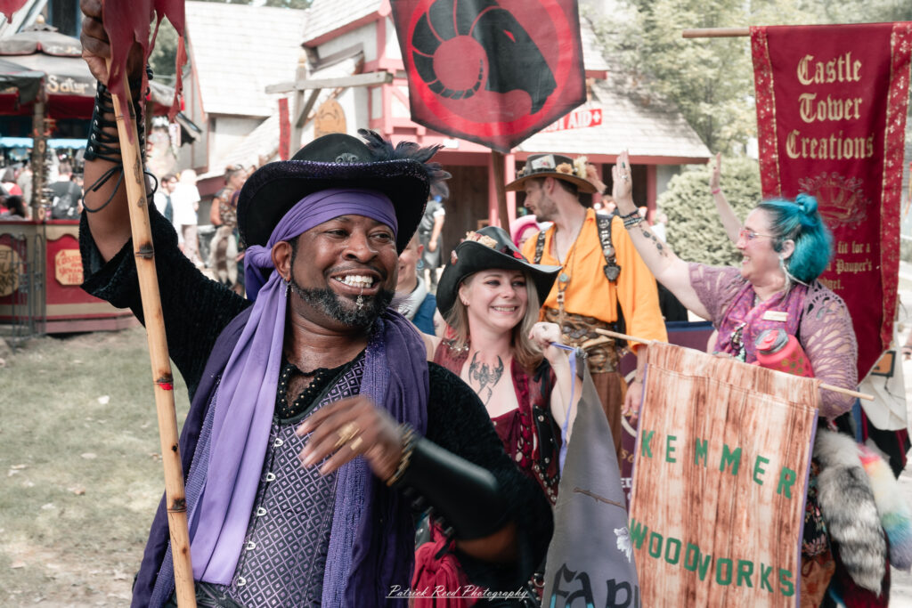A costumed performer at the Michigan Renaissance Festival 2025, wearing traditional Renaissance attire during a live event in Holly, Michigan.