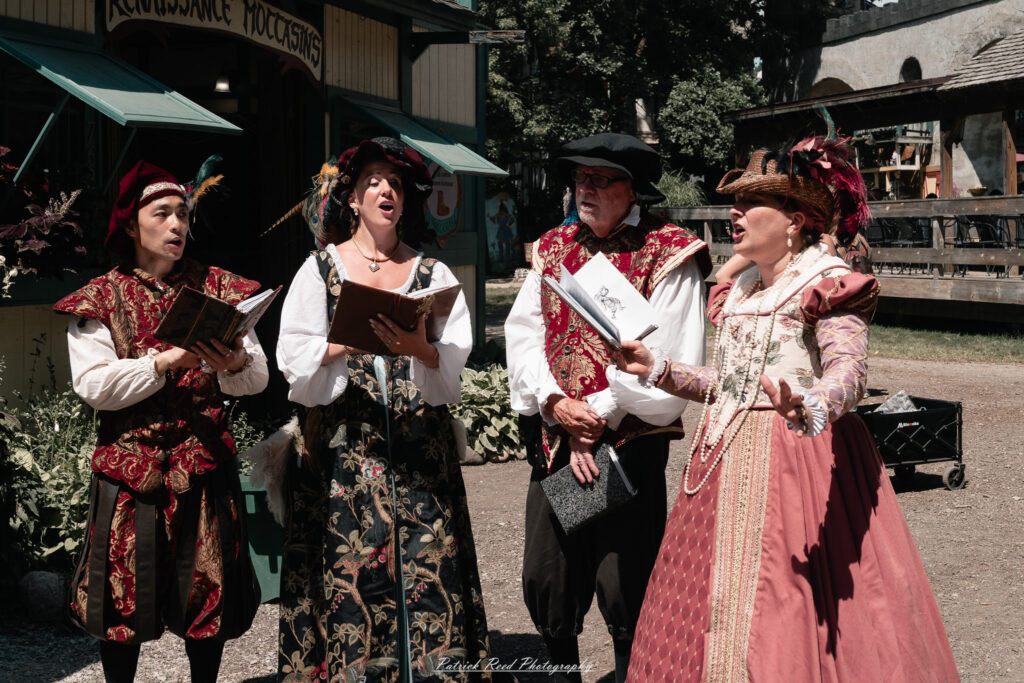 A costumed performer at the Michigan Renaissance Festival 2025, wearing traditional Renaissance attire during a live event in Holly, Michigan.