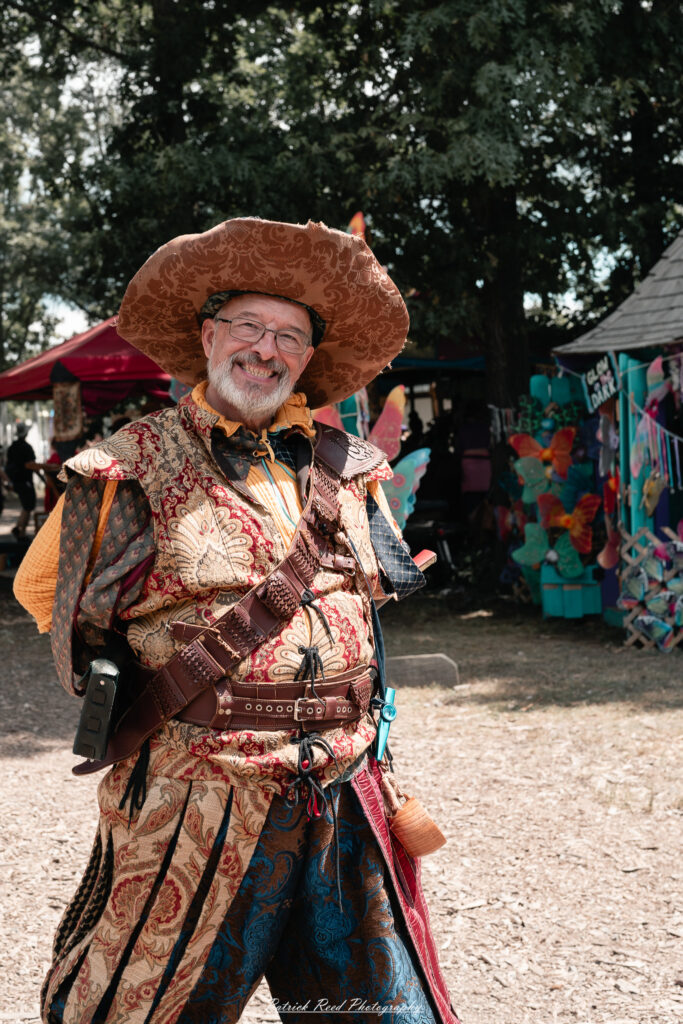 A costumed performer at the Michigan Renaissance Festival 2025, wearing traditional Renaissance attire during a live event in Holly, Michigan.