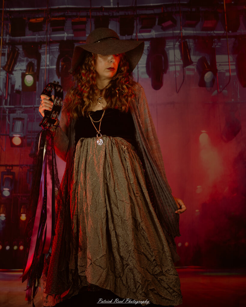 A woman dressed in flowing bohemian attire, channeling Stevie Nicks with layered fabrics, soft textures, and moody lighting.