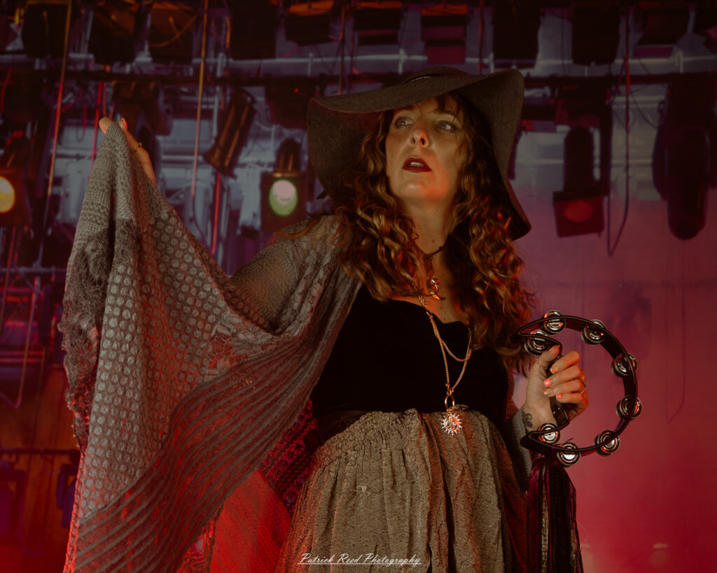 A woman dressed in flowing bohemian attire, channeling Stevie Nicks with layered fabrics, soft textures, and moody lighting.