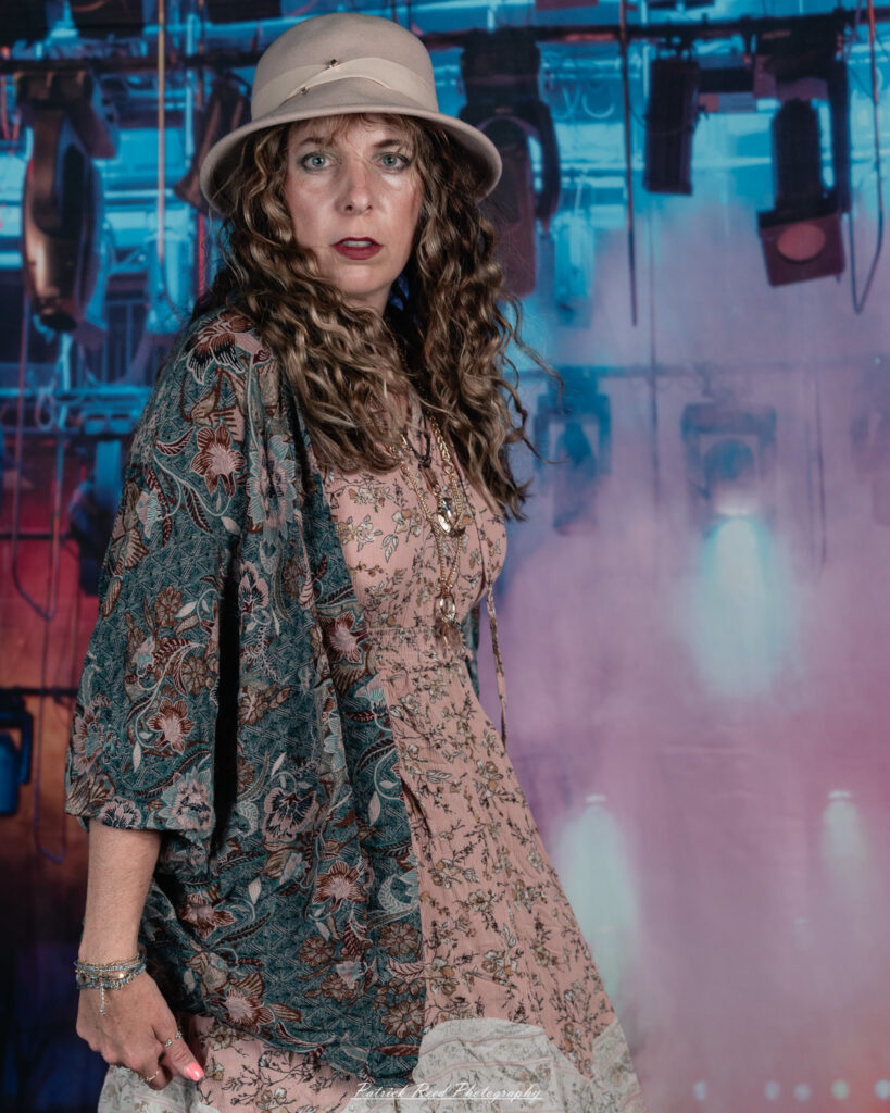 A woman dressed in flowing bohemian attire, channeling Stevie Nicks with layered fabrics, soft textures, and moody lighting.