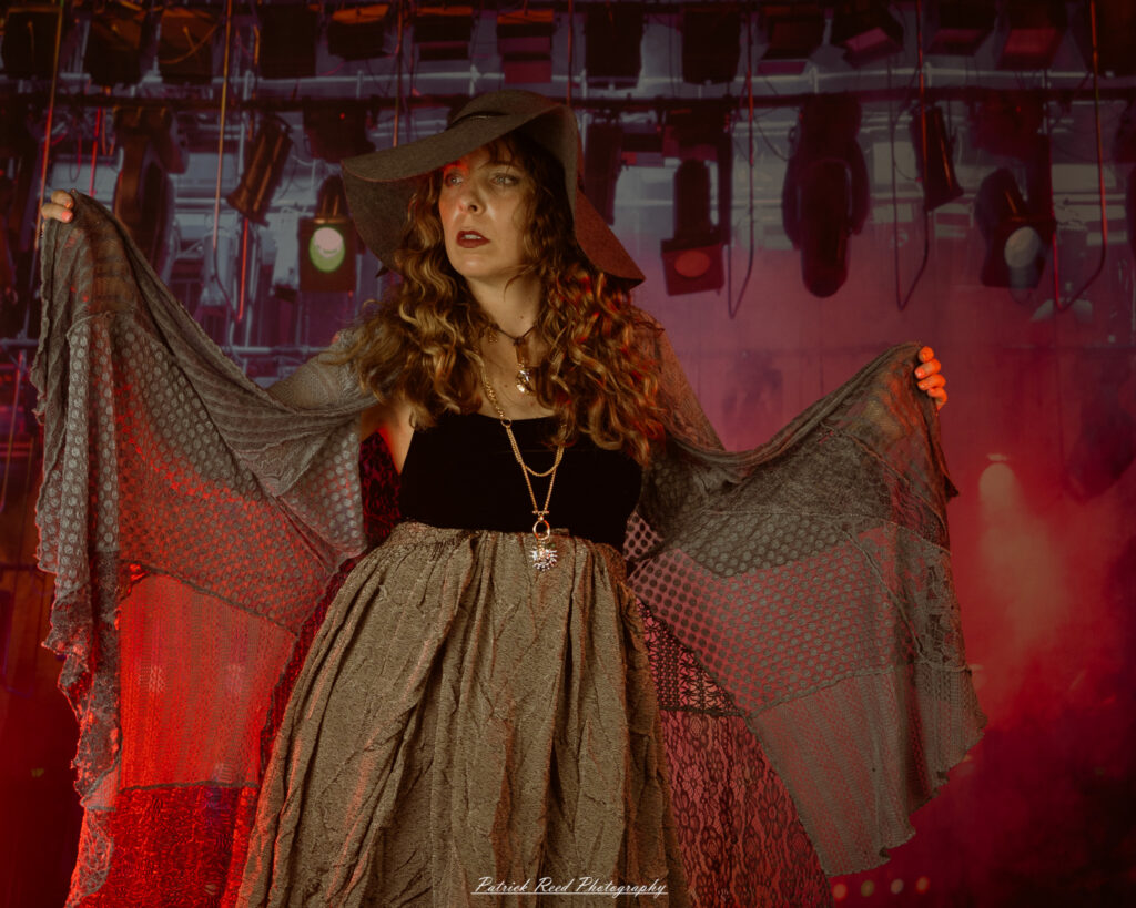 A woman dressed in flowing bohemian attire, channeling Stevie Nicks with layered fabrics, soft textures, and moody lighting.
